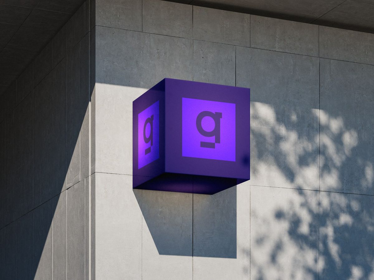 Enseigne 9Squad : cube lumineux violet portant le monogramme, fixé sur une façade en béton